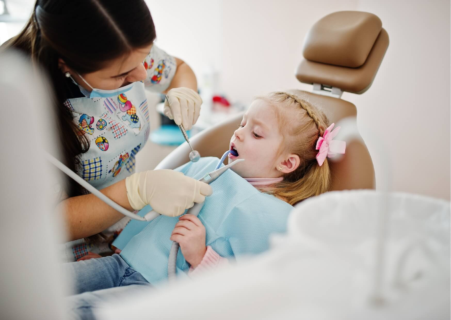 Young child receiving pediatric dental care, including assessment and placement of a dental spacer to preserve space for permanent teeth.